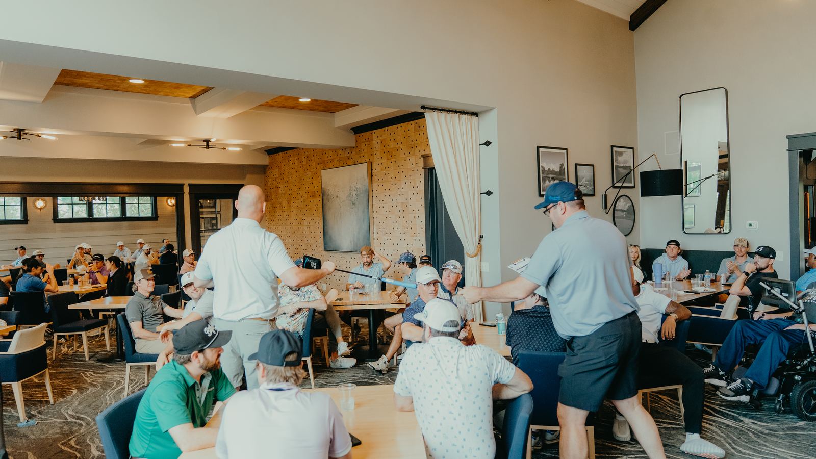 The awards reception at the 2026 TShaw Strong Celebrity Golf Classic. Golfers fill the clubhouse at Westhaven while prizes are handed out; Tim Shaw is at the right of the room in his power wheelchair.