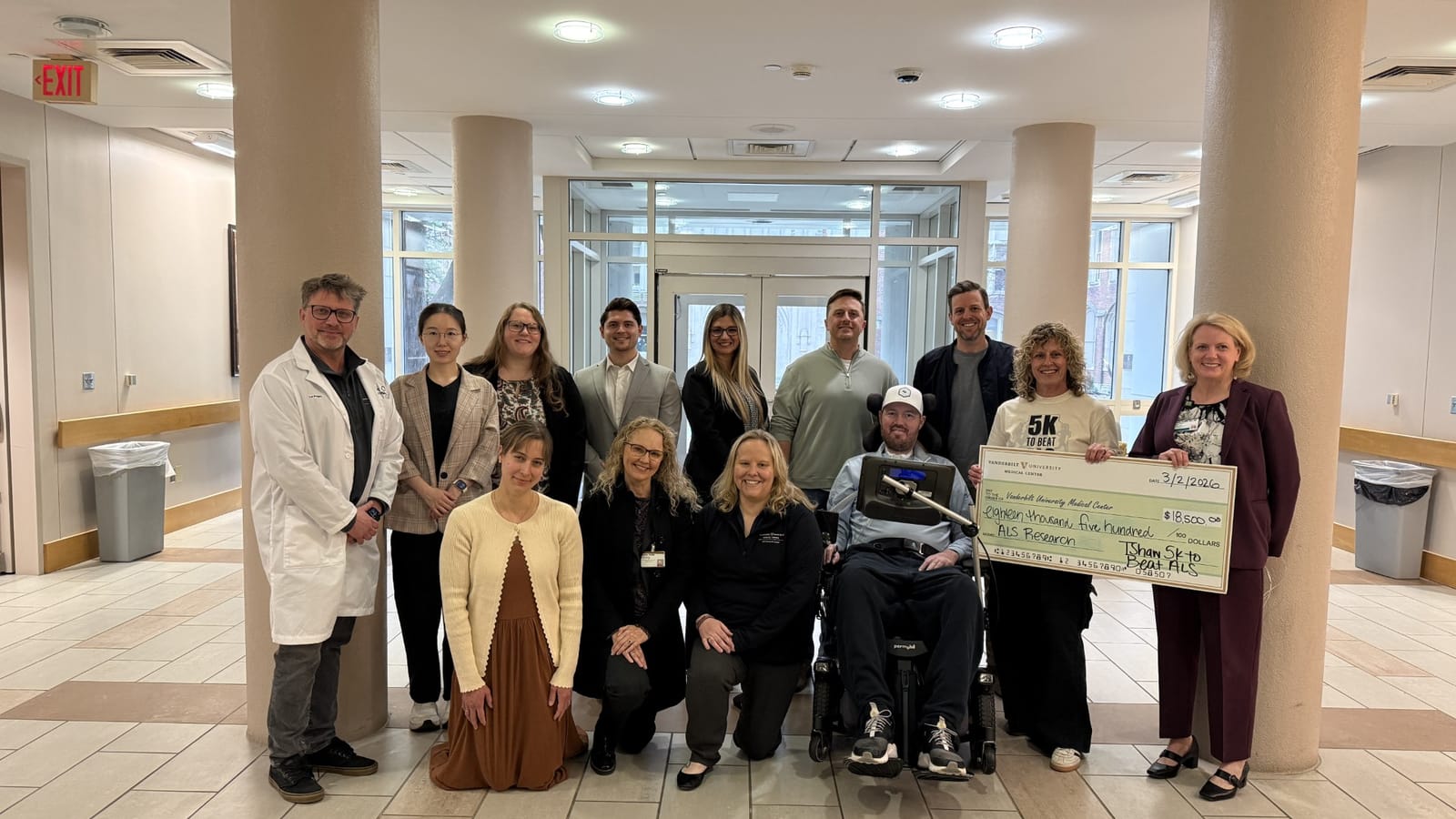 Tim Shaw with the Vanderbilt ALS Research Center team in a Vanderbilt lobby, March 2, 2026. A presentation check for $18,500 made out to Vanderbilt University Medical Center, memo 'ALS Research', is held up beside him.